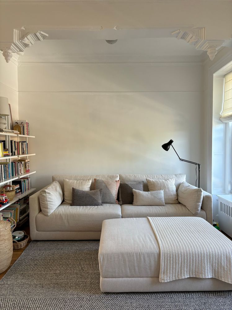 Beige sectional couch in a living room with several throw pillows on it.